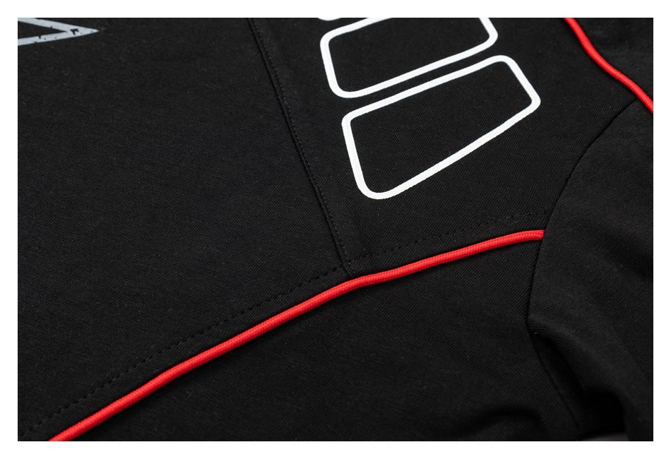Close-up of a black shirt's stitched panel and bright red piping beneath a white graphic.