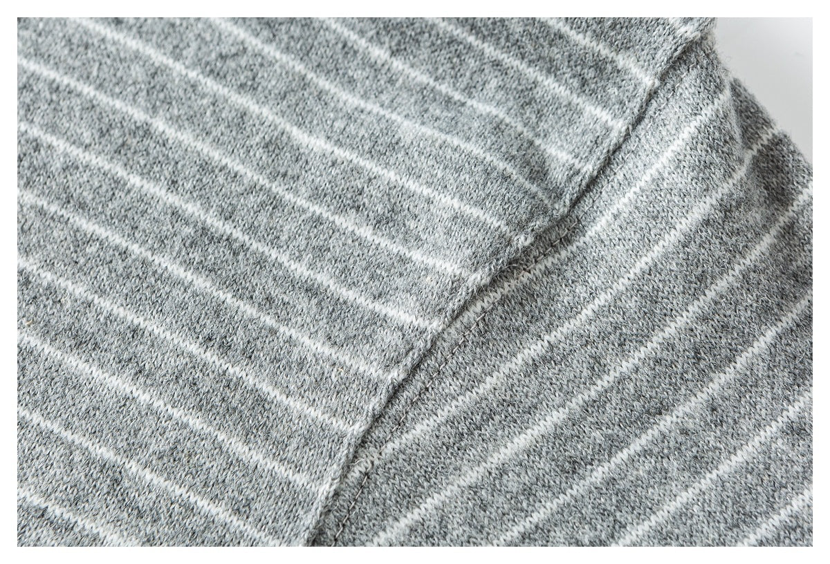 Close-up of a seam joining panels of gray knit fabric with narrow white stripes.