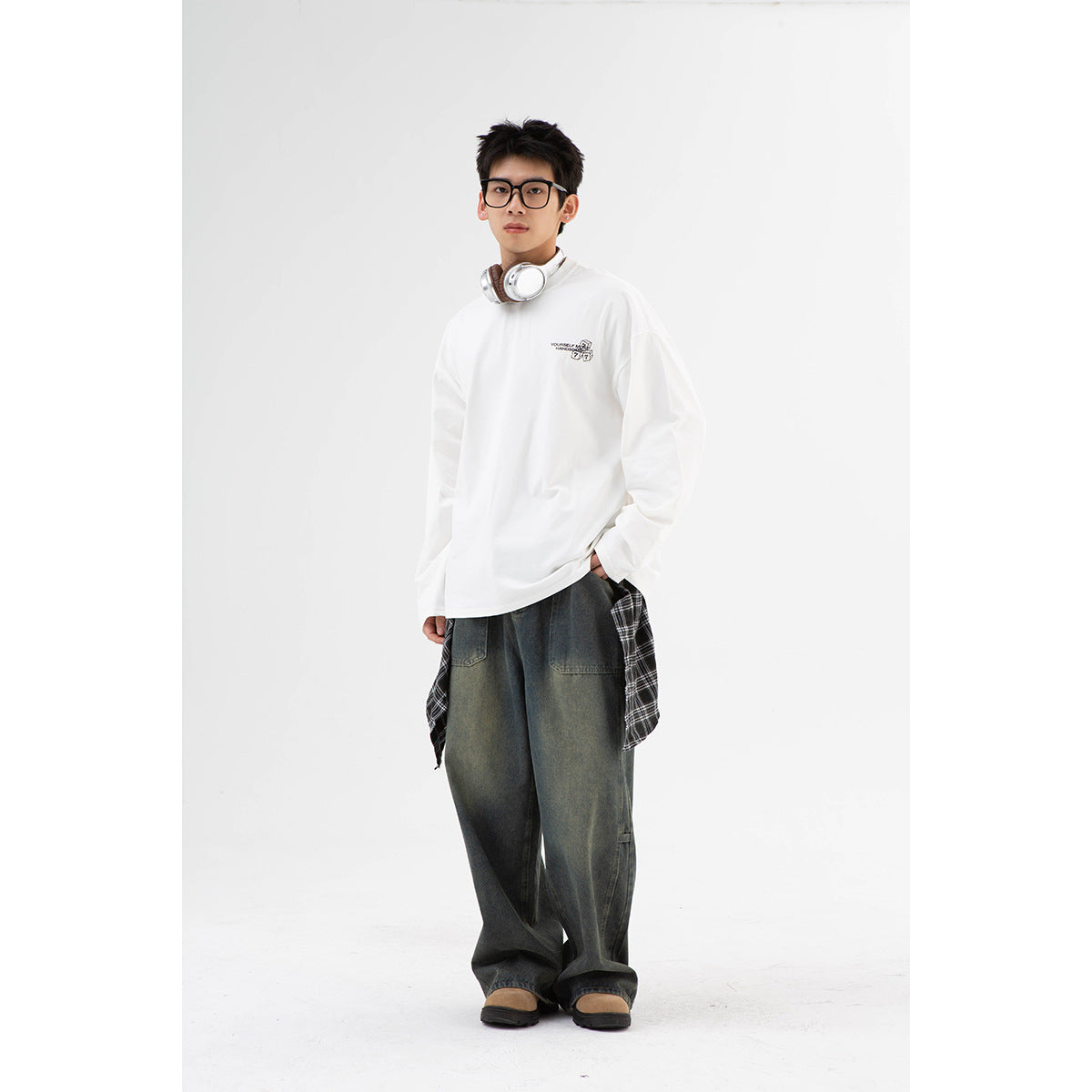 Full-length front view of a model wearing an oversized white long-sleeve shirt with a small chest graphic.
