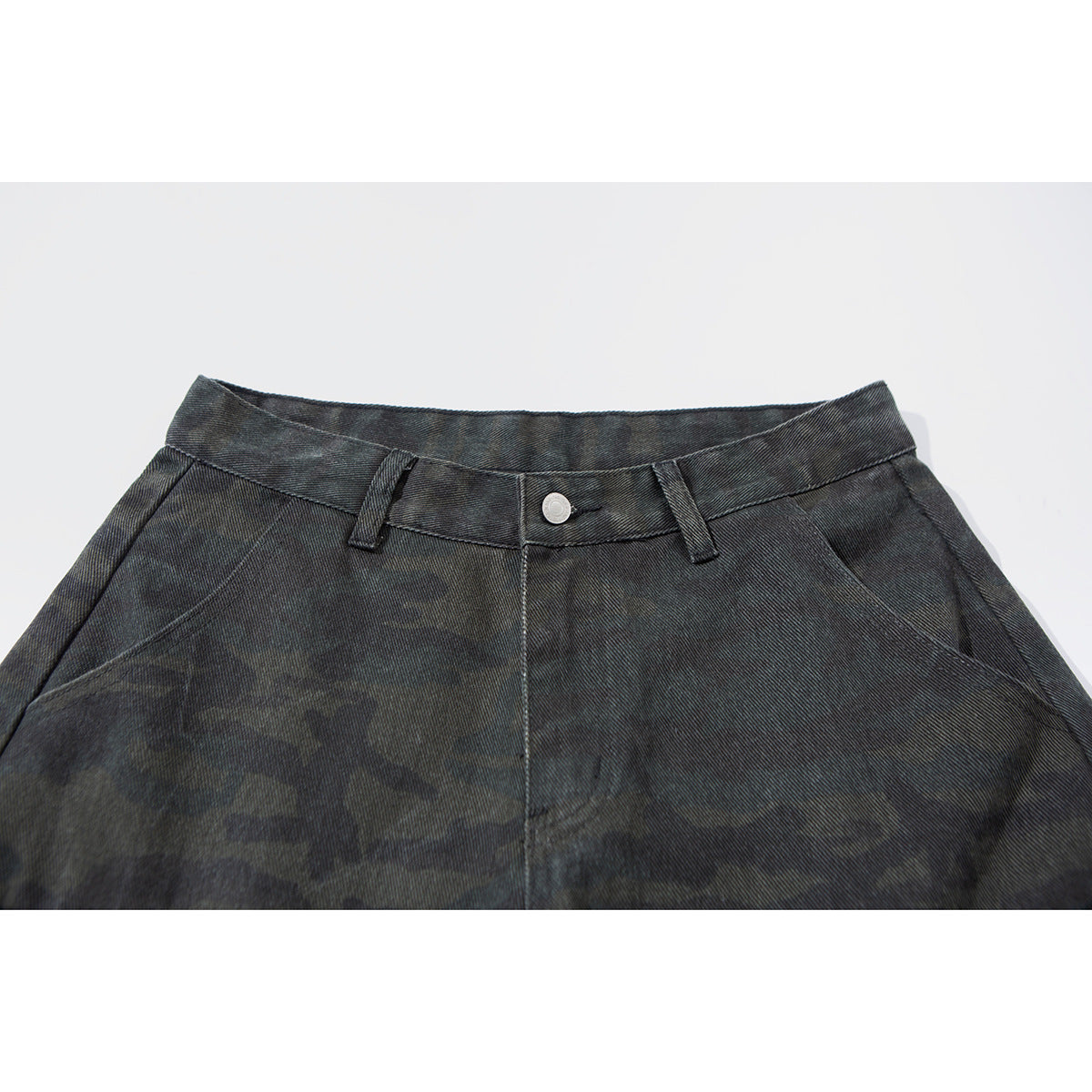 Close-up of dark charcoal camouflage cargo pants showing the waistband, button, belt loops and front pockets.