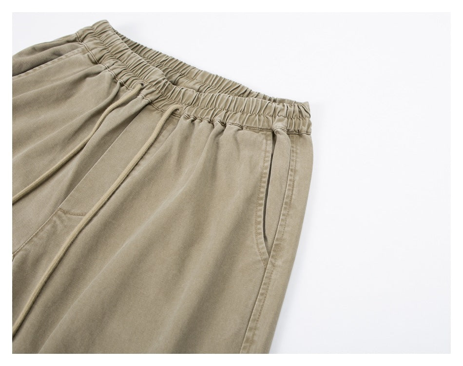 Angled close-up of the beige pants’ elastic waistband and side pocket.