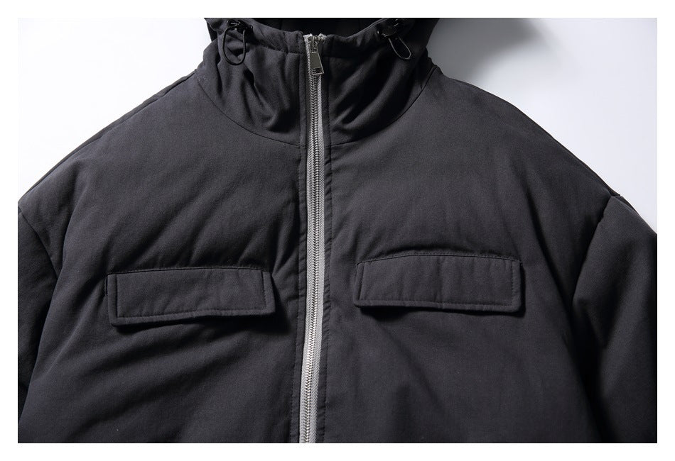 Close-up of the black jacket's front zipper and two flap chest pockets.