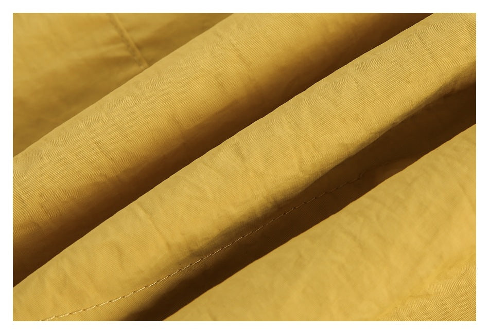 Close-up of folded mustard-yellow fabric with a visible line of stitching.