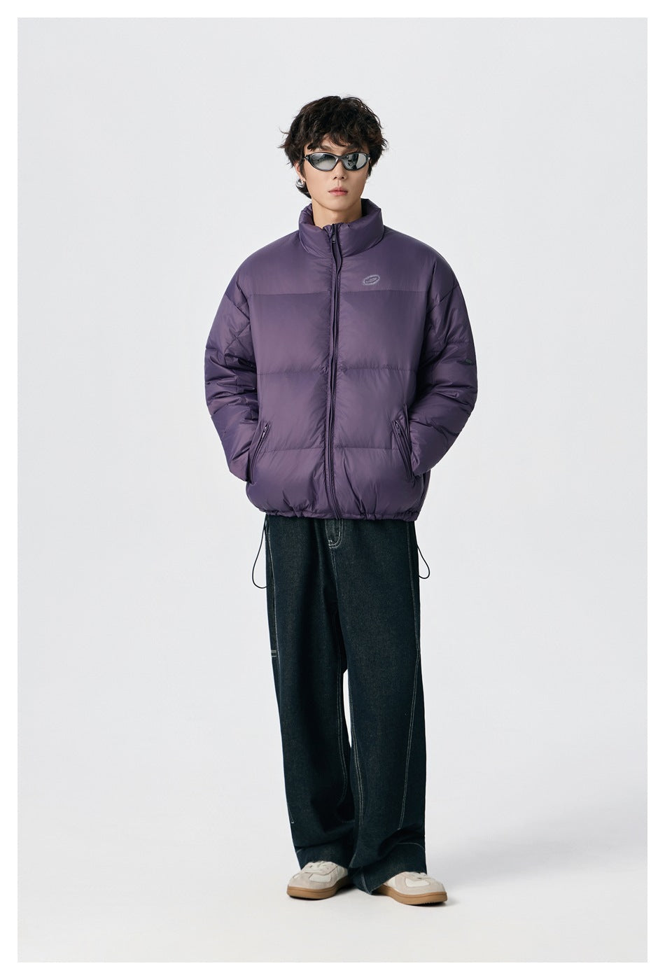 Model wearing a purple quilted puffer jacket with a high collar, front zip, and side pockets.