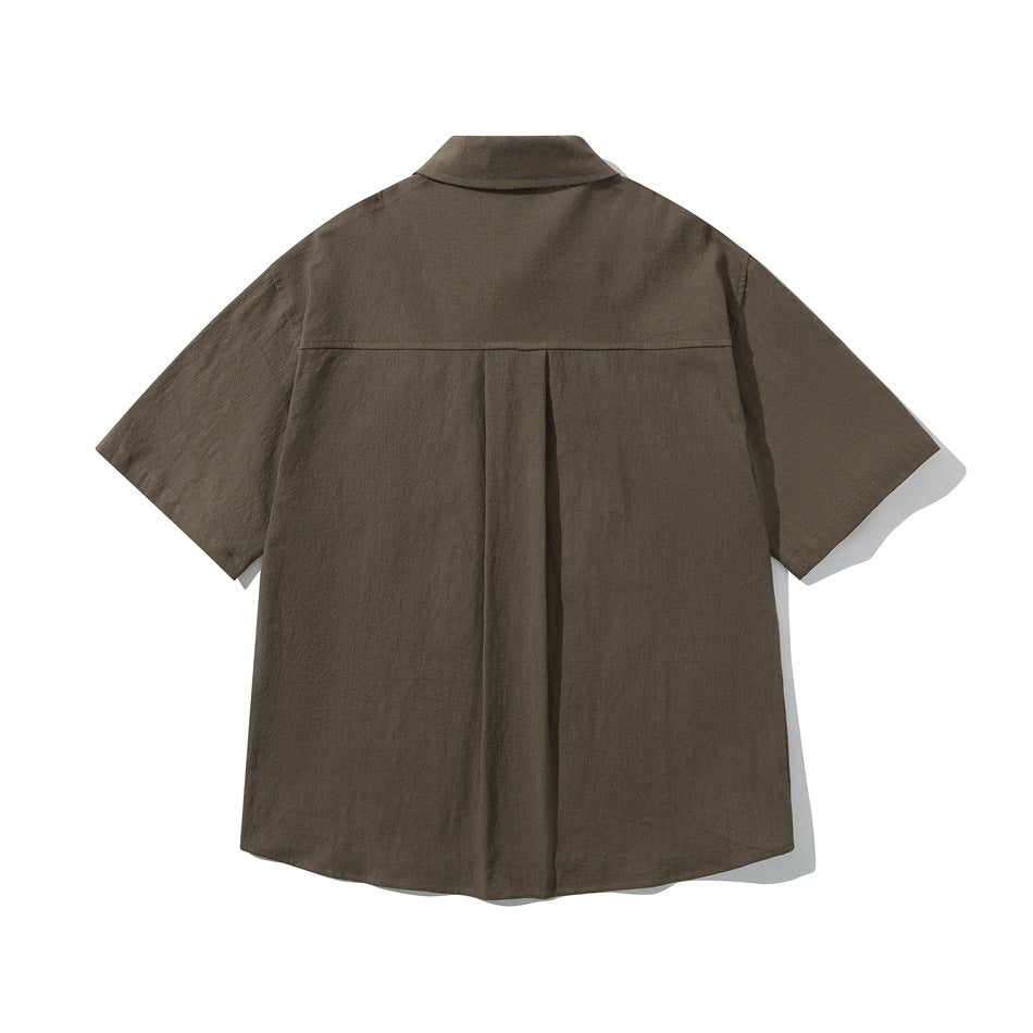 Back view of brown short-sleeve shirt showing yoke seam and center box pleat, flat lay