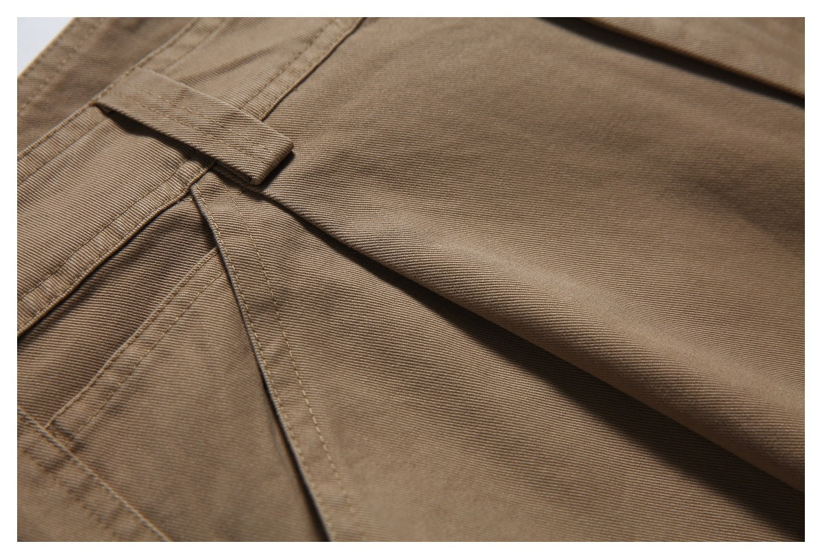 Close-up of tan trousers showing a belt loop and angled pocket stitching.