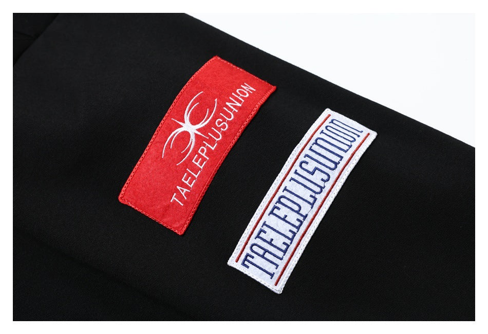 Close-up of two rectangular red and white embroidered patches on black fabric.
