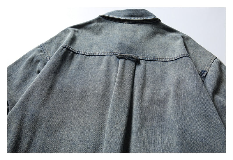 Back view of a faded blue denim shirt laid flat, showing the yoke seam and center pleat.