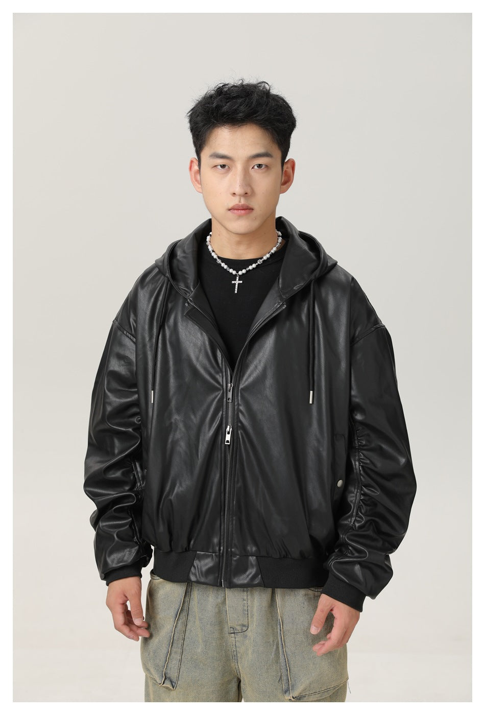 Model wearing a black glossy hooded zip jacket with an oversized fit, drawstrings, and ribbed cuffs and hem.