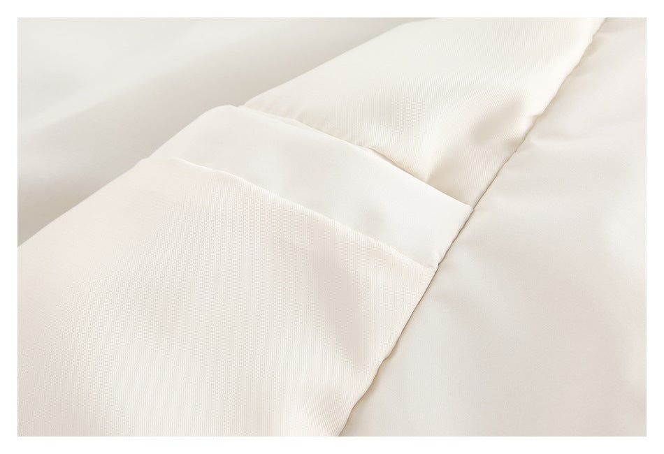 Close-up of an off-white garment showing a wide stitched seam between fabric panels.