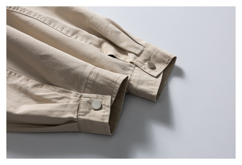 Close-up of beige garment sleeves with stitched cuffs and round snap buttons.
