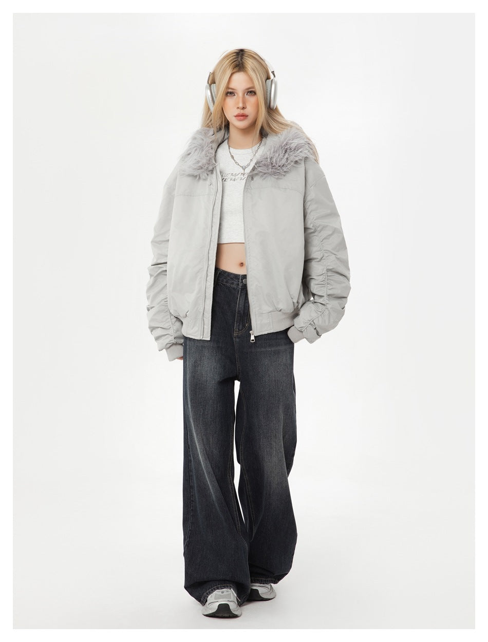 Model wearing a light gray hooded bomber jacket with faux-fur-textured trim, cropped white top and wide-leg dark jeans