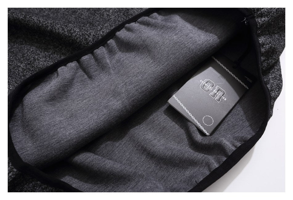 Inside view of dark heather-gray garment with a black-edged opening and a branded hang tag.