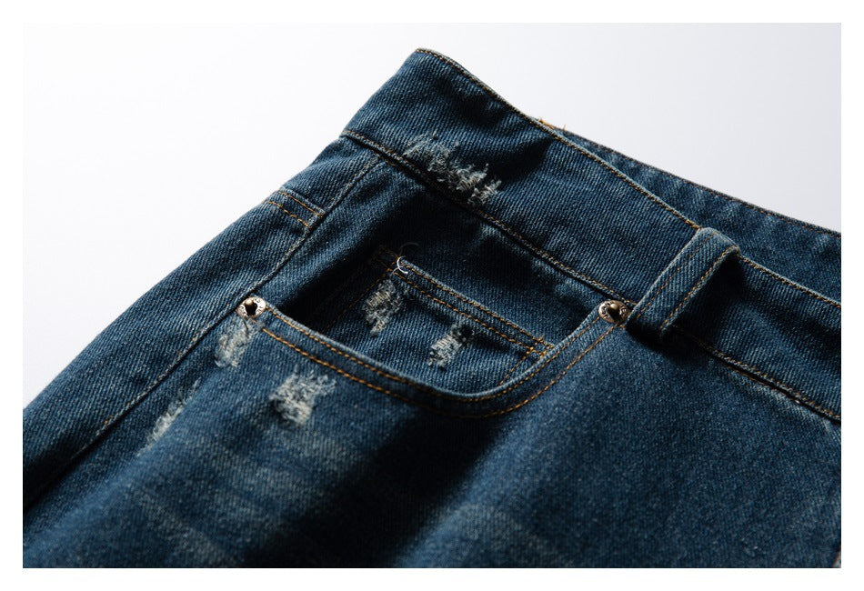 Close-up of dark blue distressed jeans showing the front coin pocket, waistband, and belt loop.