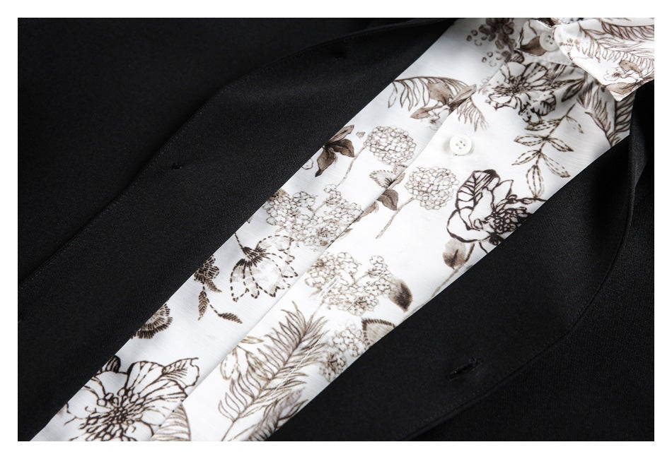 Close-up of a black jacket lapel over a white shirt with brown floral print and white buttons.