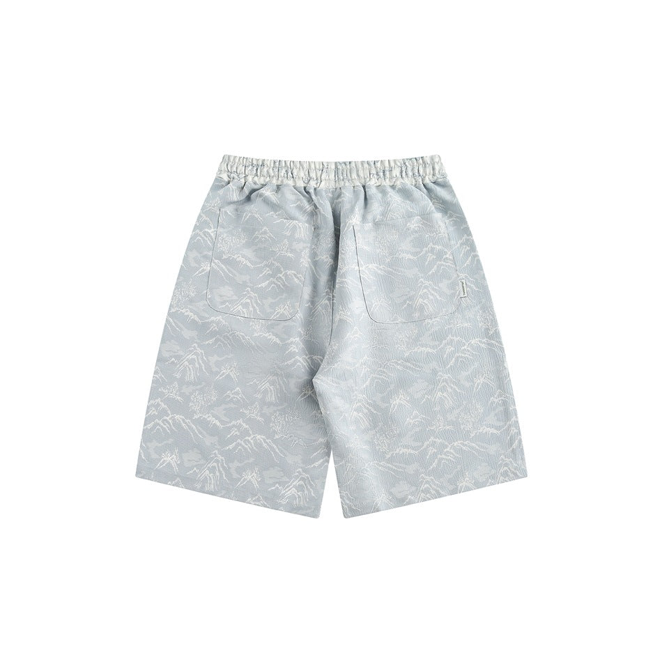 Back view of light blue shorts with white mountain pattern, elastic waistband and two patch pockets