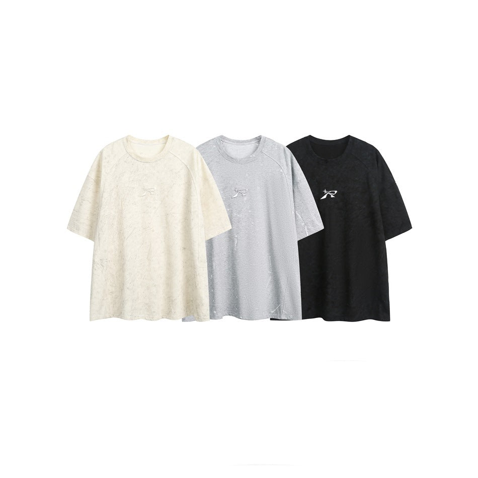 Three oversized short-sleeve T-shirts with small chest emblems, shown in ivory, light gray, and black.