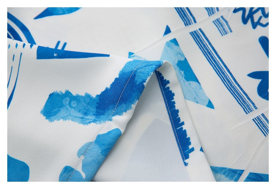 Close-up of white fabric with a blue abstract print and a stitched folded edge.