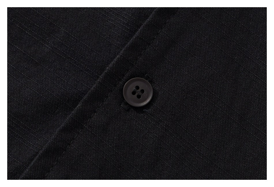 Close-up of a dark four-hole button and stitching on black shirt fabric.