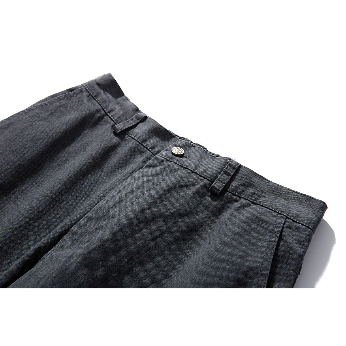 Close-up of charcoal-gray trousers showing the waistband, belt loops, button, and front pleats.