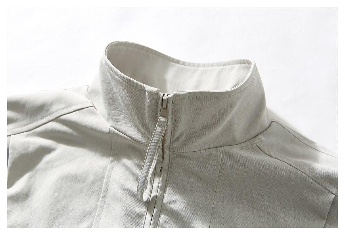 Close-up of an off-white jacket's stand collar and front zipper with a long matching pull tab.