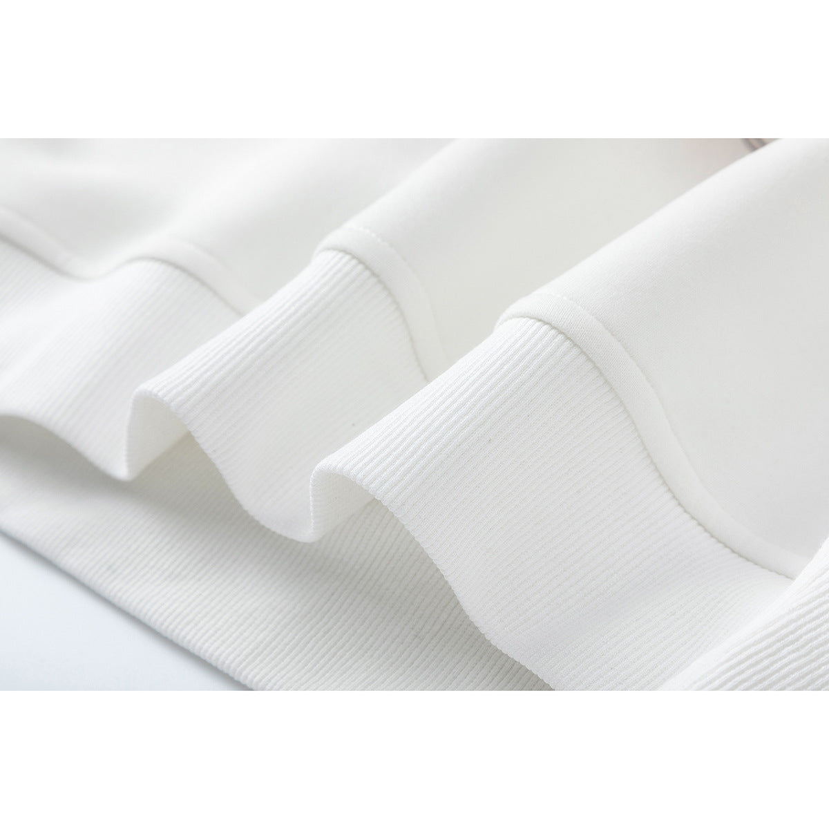 Close-up of a white sweatshirt’s ribbed hem and smooth fabric.
