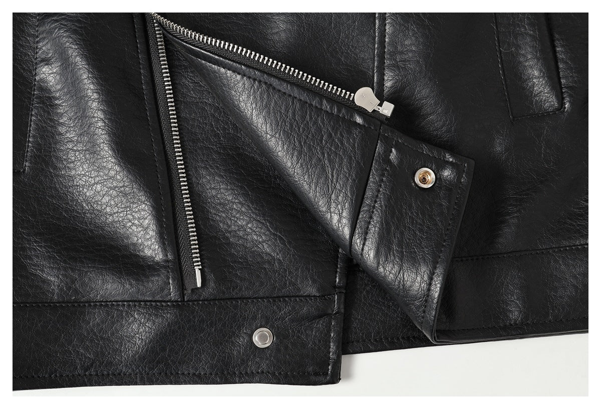 Close-up of the black jacket's lower front with zippers, a snap fastener and stitched panels.