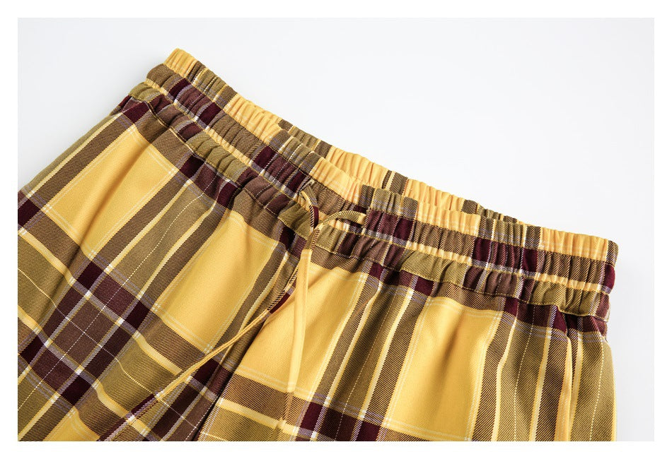 Close-up of the gathered elastic waistband and drawstring on mustard yellow plaid pants.