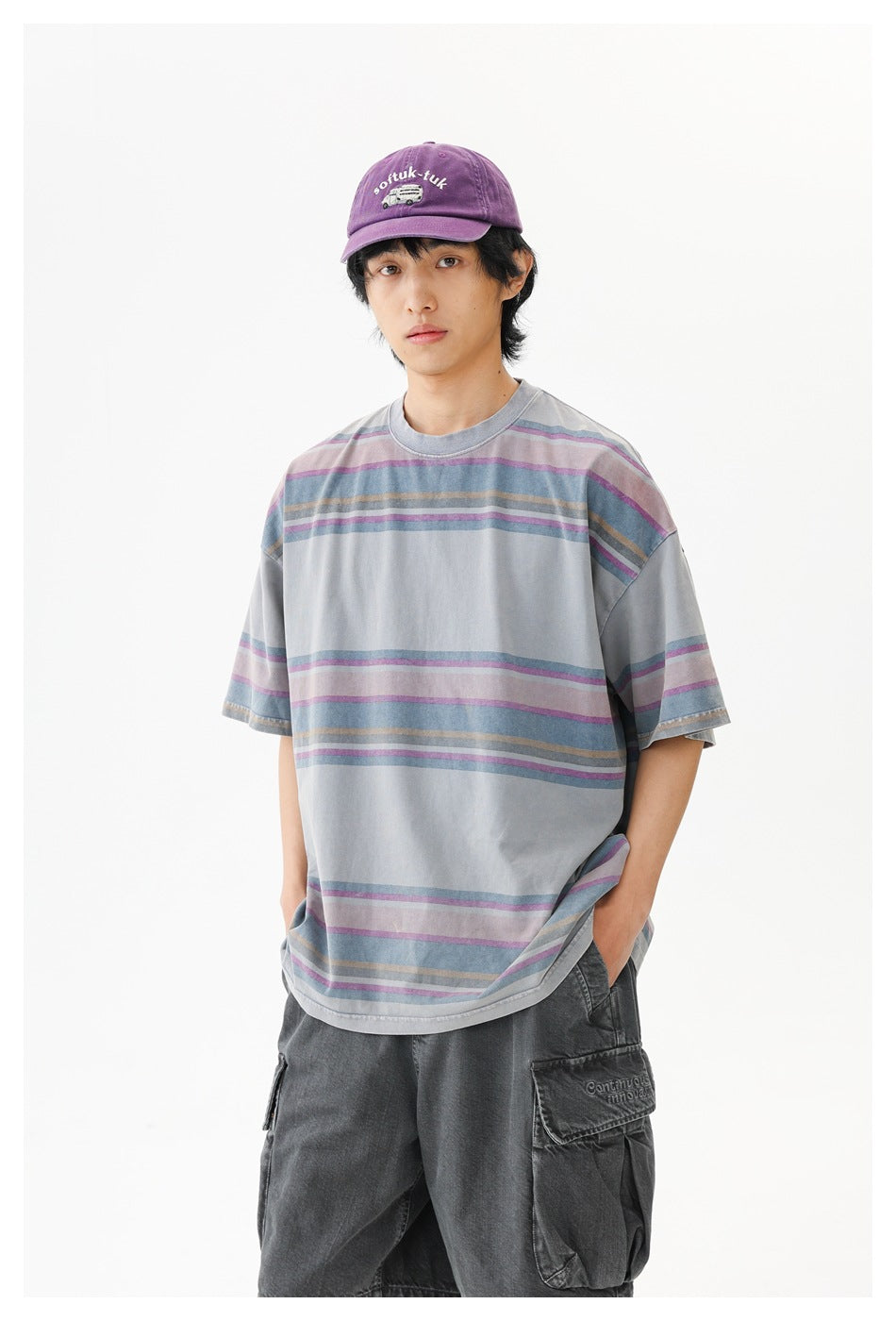 Closer front view of a model in an oversized gray T-shirt with muted purple, blue, and tan horizontal stripes.
