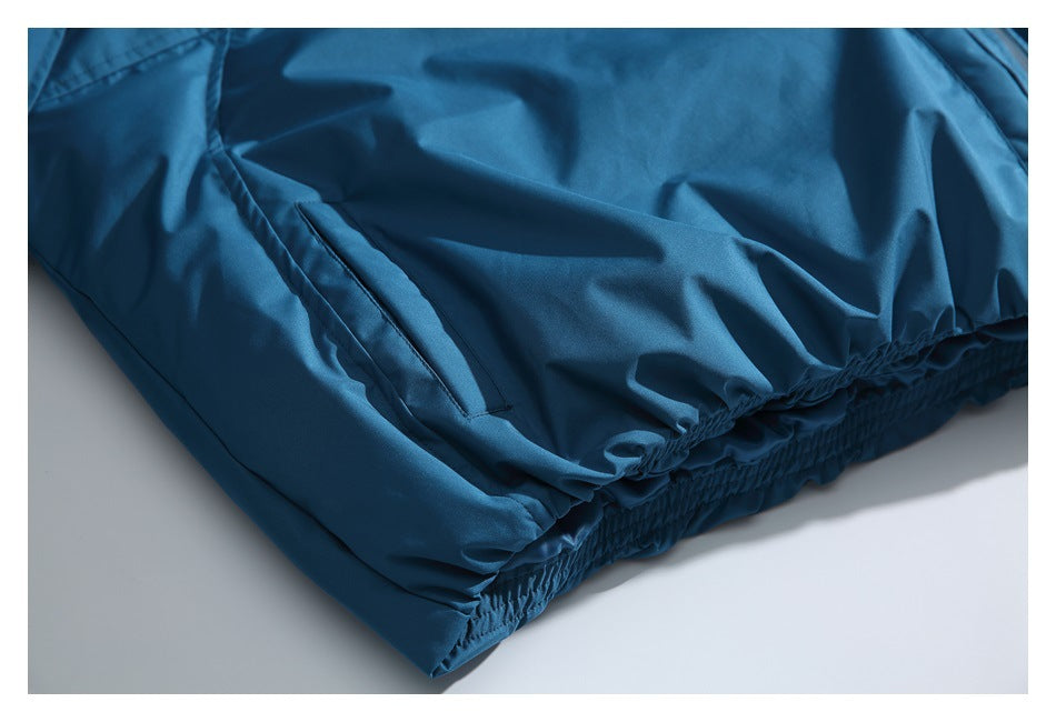 Close-up of a slanted pocket and gathered elastic hem on a teal-blue jacket.