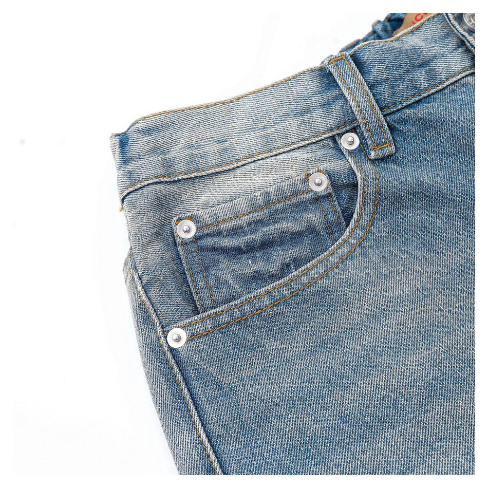 Close-up of a front pocket and small coin pocket with metal rivets on faded blue jeans.