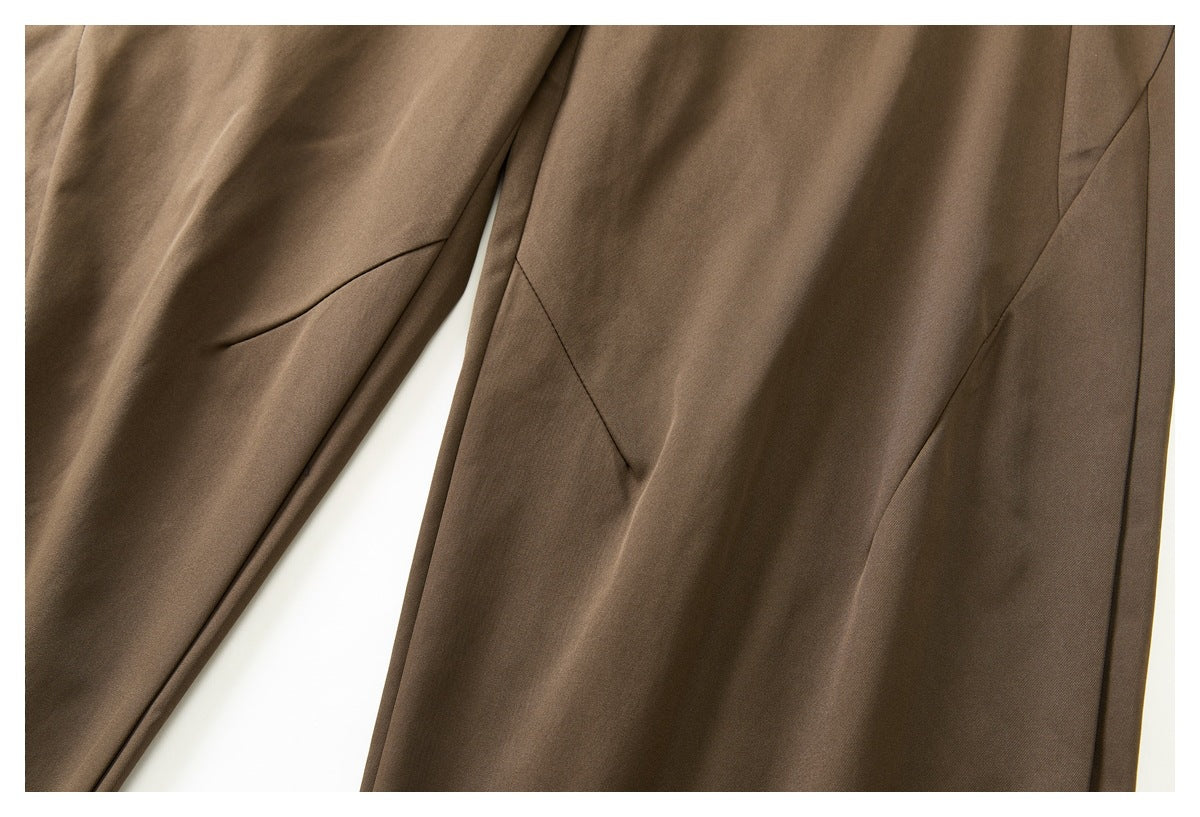 Close-up of brown trouser legs showing angled seam details and a narrow welt pocket.