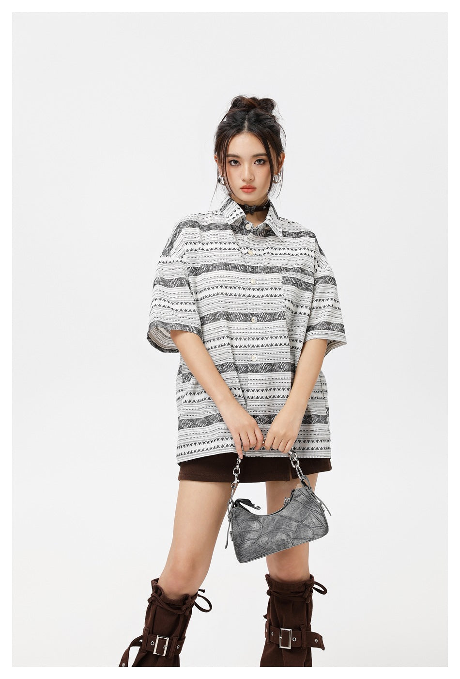 Closer view of a model wearing an oversized white shirt with black geometric stripes over a brown mini skirt.