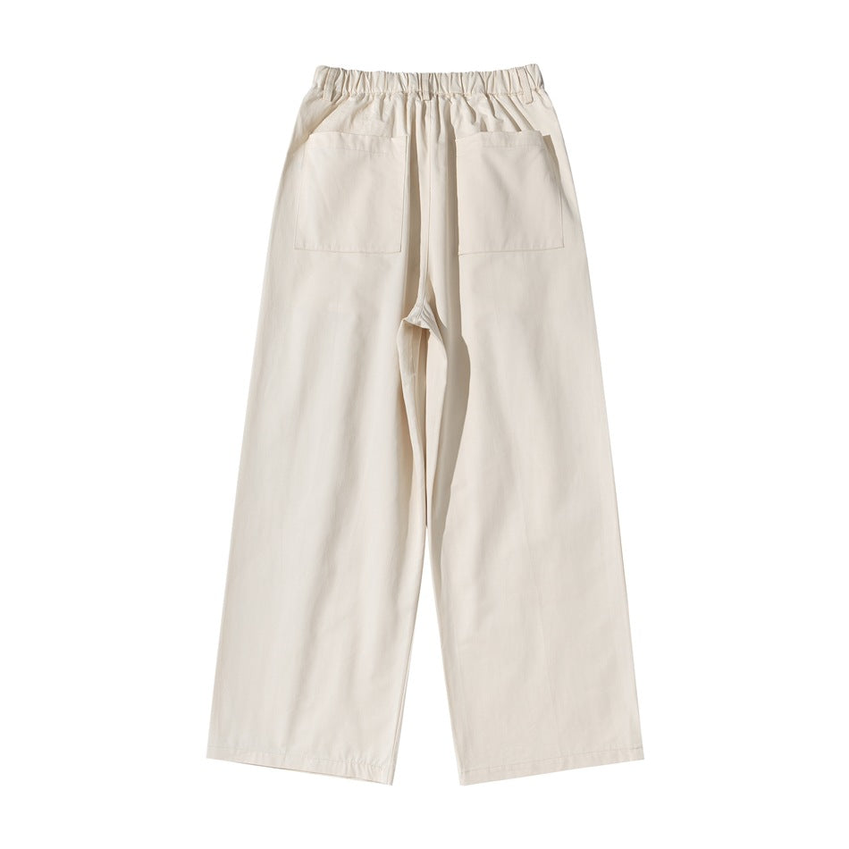 Back view of beige wide-leg pants with elastic waistband and two large patch pockets, flat lay