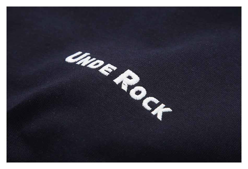 Close-up of white embroidered lettering on dark navy fabric.
