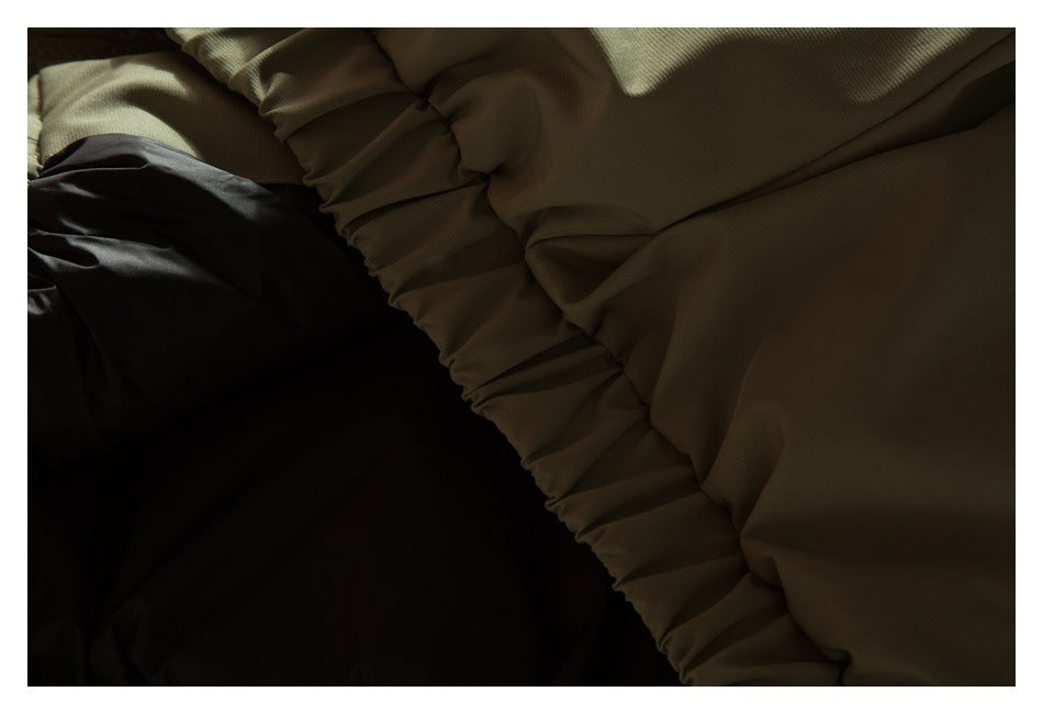 Dark close-up of olive-khaki garment fabric and a gathered seam.
