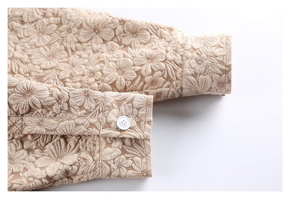 Close-up of the beige garment's floral-textured sleeve cuffs, showing a white button on one cuff.