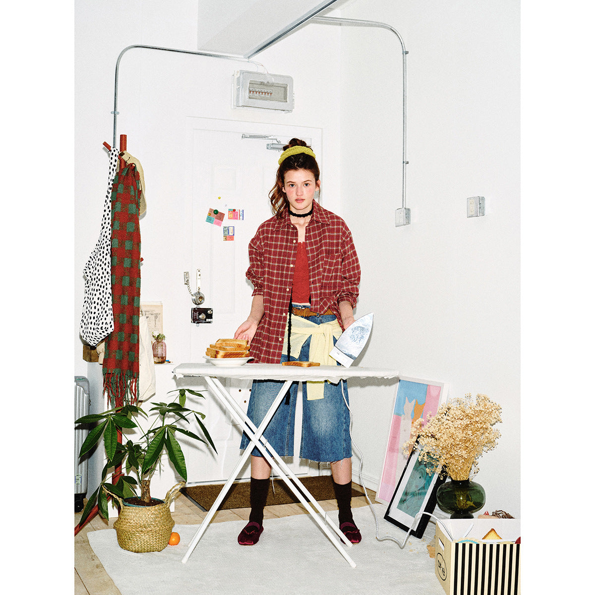 Full-length model wearing a red plaid button-up shirt with blue denim culottes and a cream layer tied at the waist.