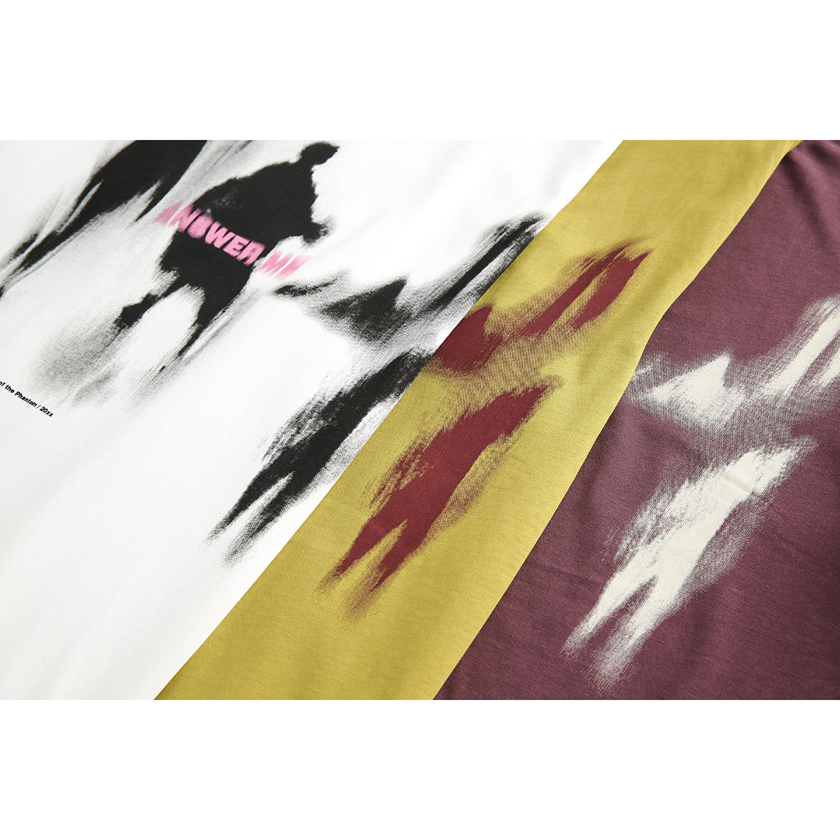 Close-up of abstract brushstroke prints on white, mustard yellow, and burgundy T-shirts.