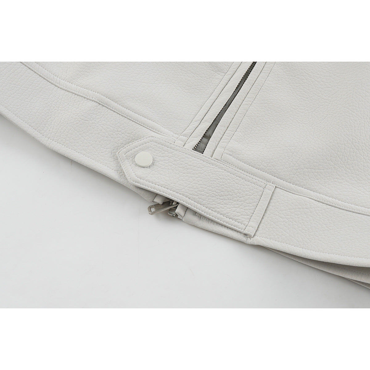 Close-up of an off-white jacket hem tab with snap and zipper hardware.