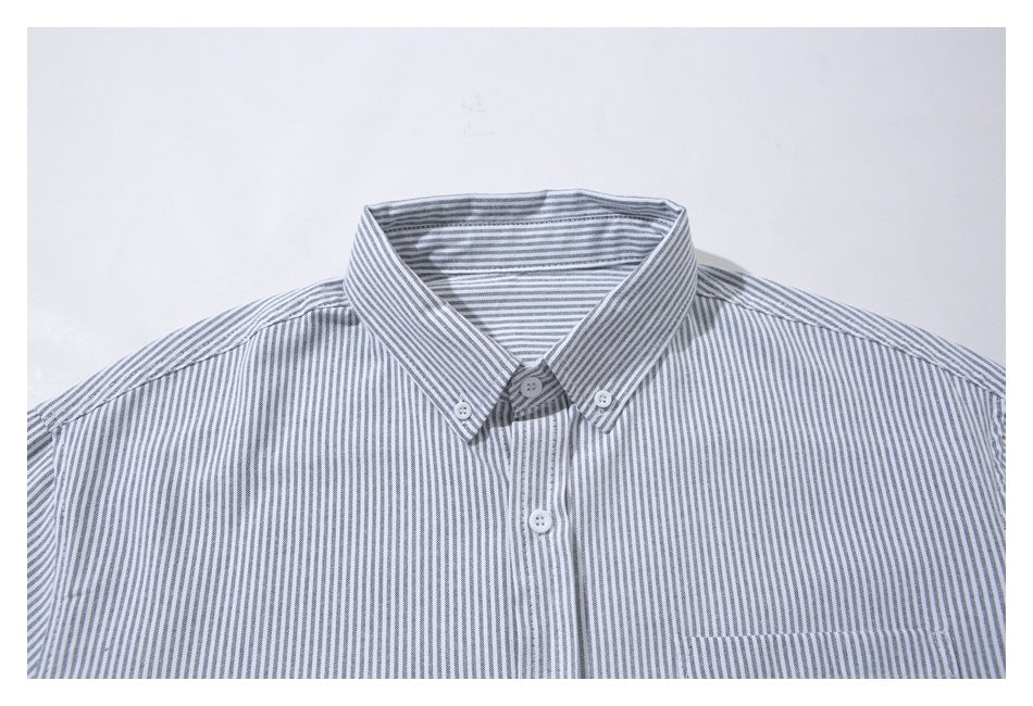 Close-up of a gray-and-white striped shirt collar, buttons, upper placket, and chest pocket.