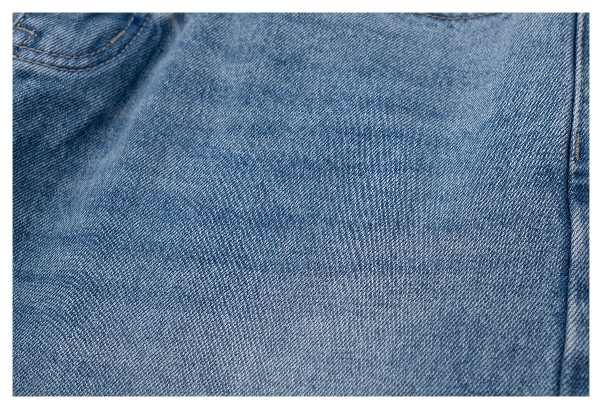 Close-up of the light blue denim fabric and a vertical stitched seam.