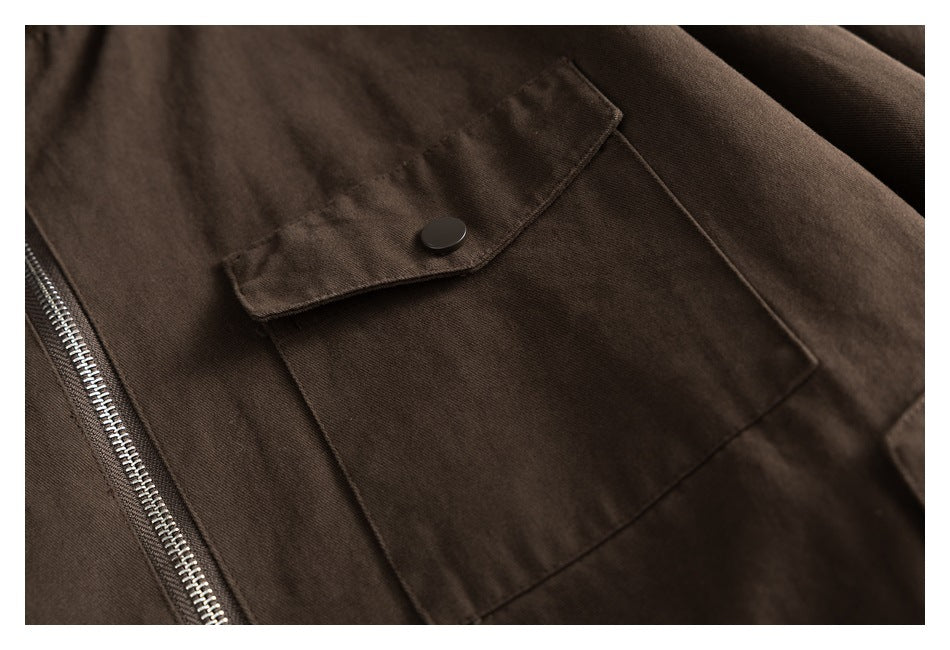 Close-up of a brown jacket pocket with a snap-button flap beside the metal zipper.