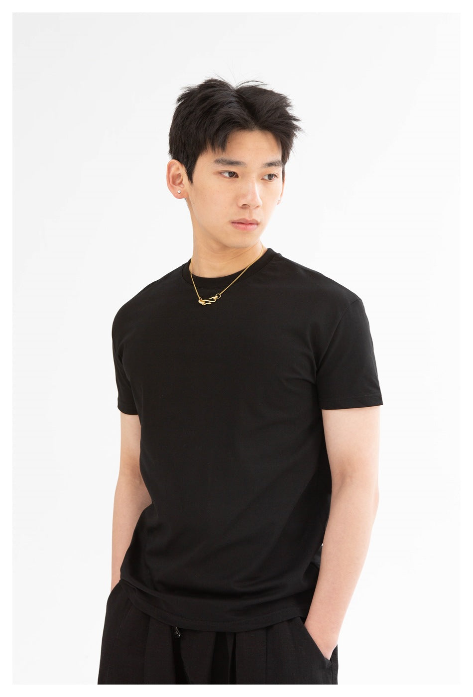 Model wearing a plain black crew-neck T-shirt, shown from the waist up at a three-quarter angle.
