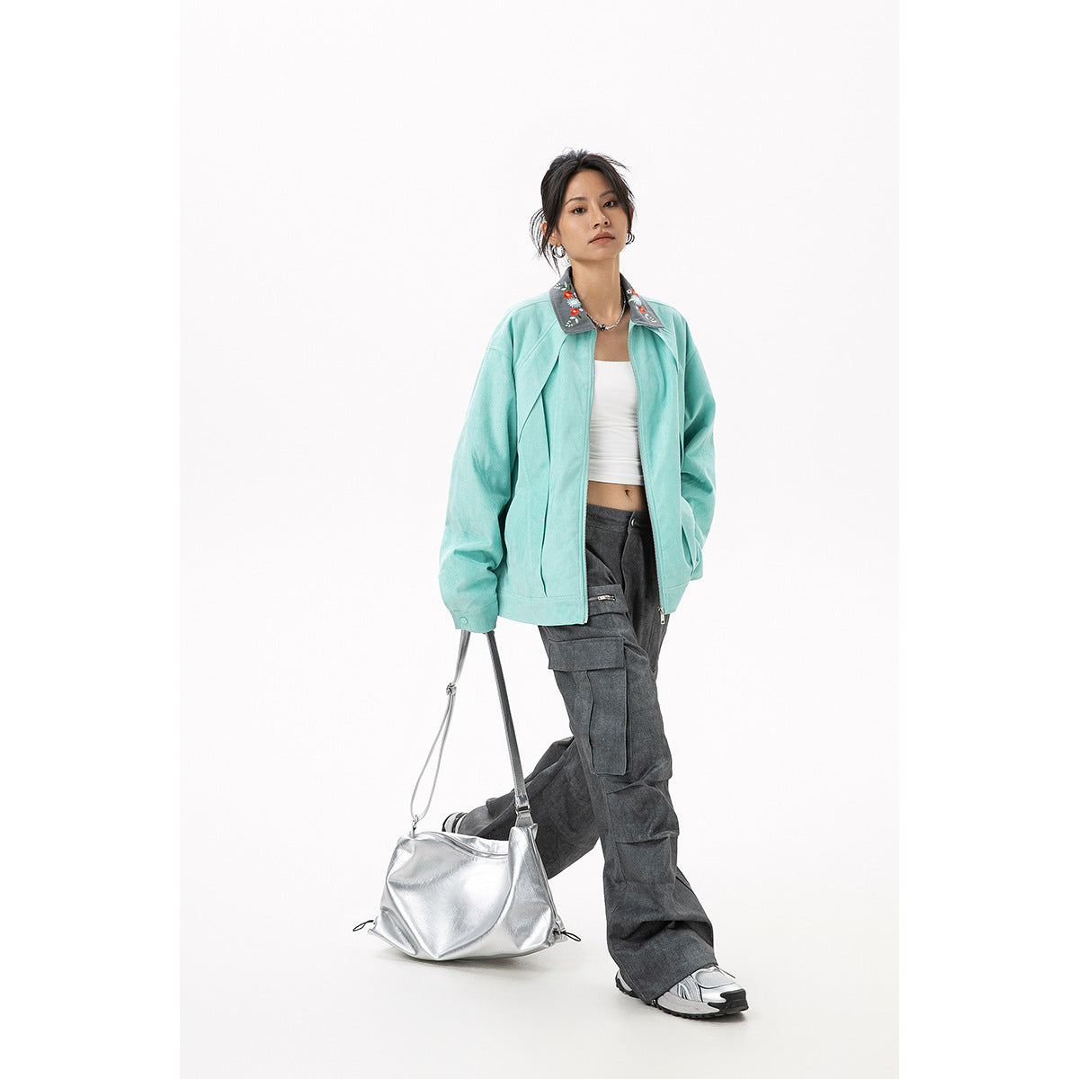 Model wearing a mint zip-front jacket with a gray floral collar, styled with charcoal cargo pants and a silver shoulder bag.