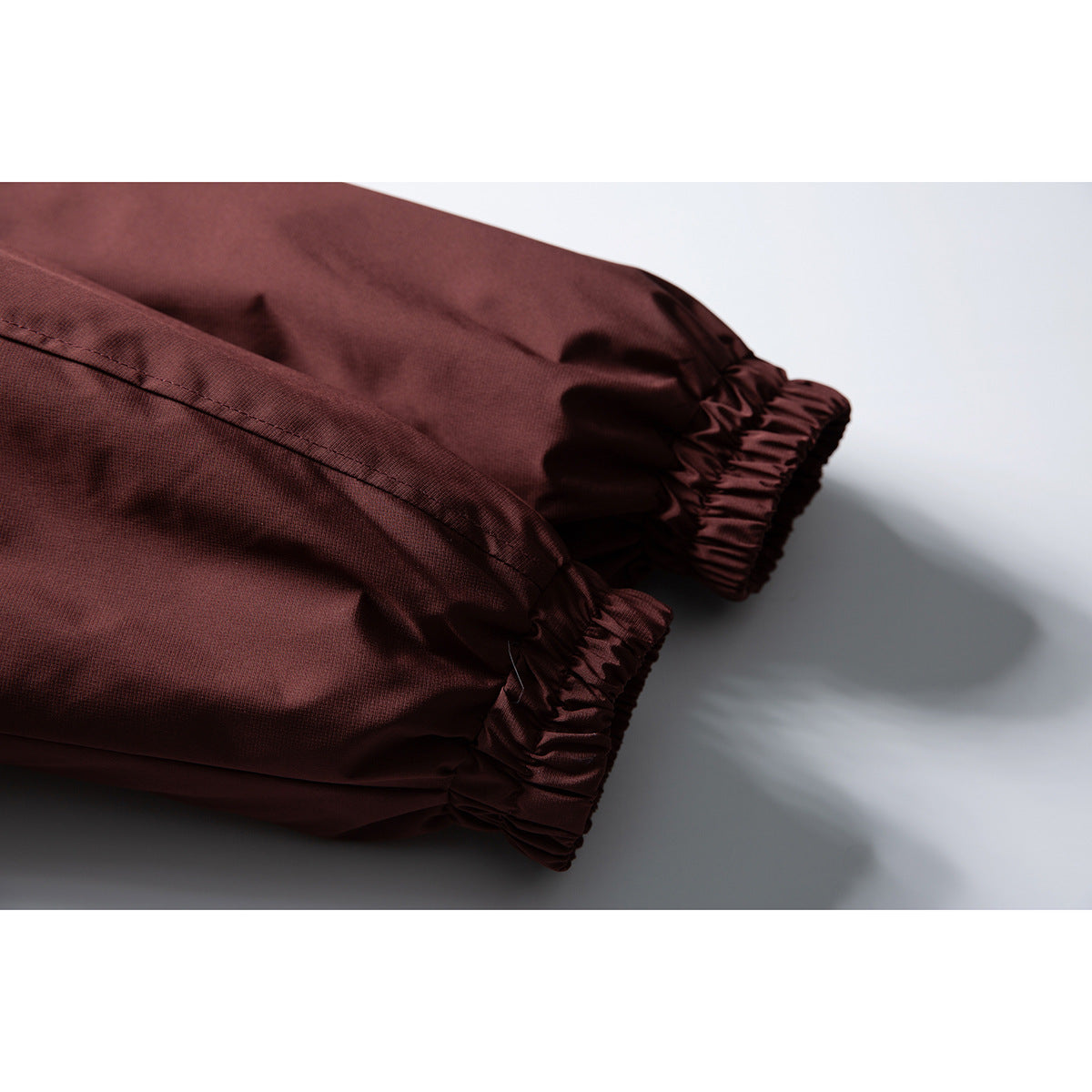Close-up of the burgundy jacket's gathered elastic cuffs and sleeve seams.