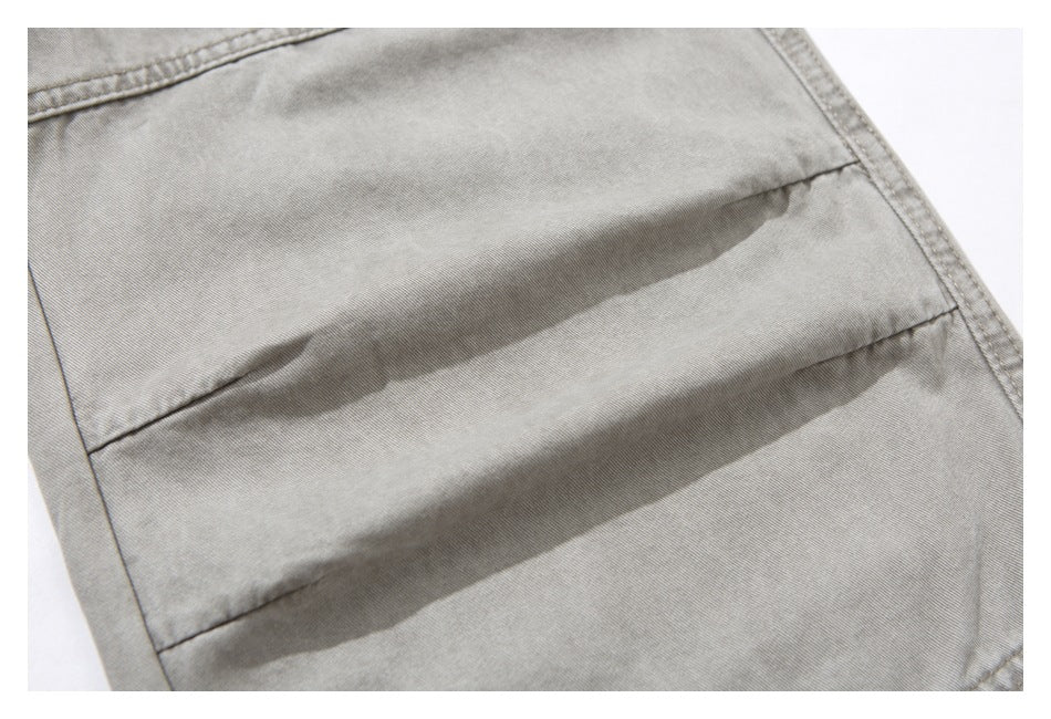 Close-up of light gray-beige trouser fabric with stitched panel seams and a folded crease.