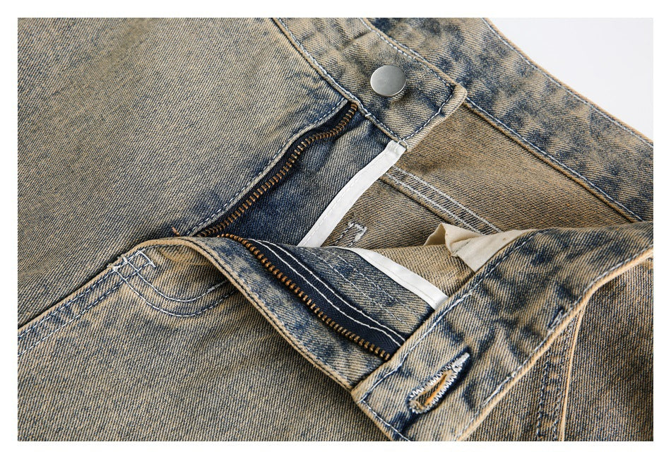 Close-up of tan acid-wash jeans with the front button and zipper fly unfastened.