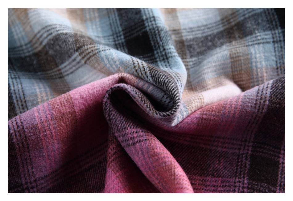Close-up of softly draped plaid fabric in plum, pink, blue-gray, black, and beige, showing its woven texture.