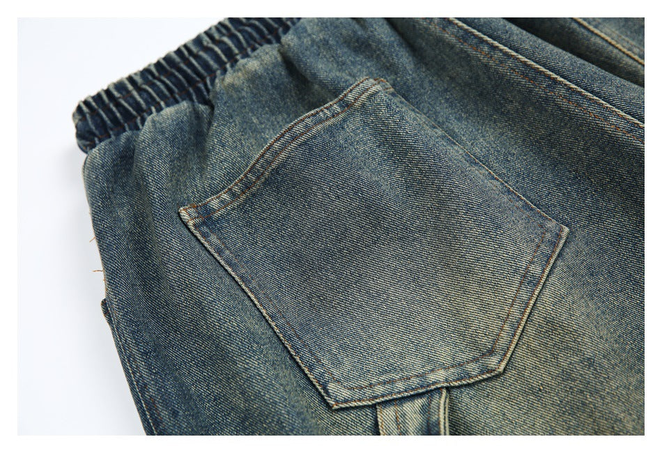 Close-up of blue washed denim pants showing an elastic waistband and a large rear patch pocket.